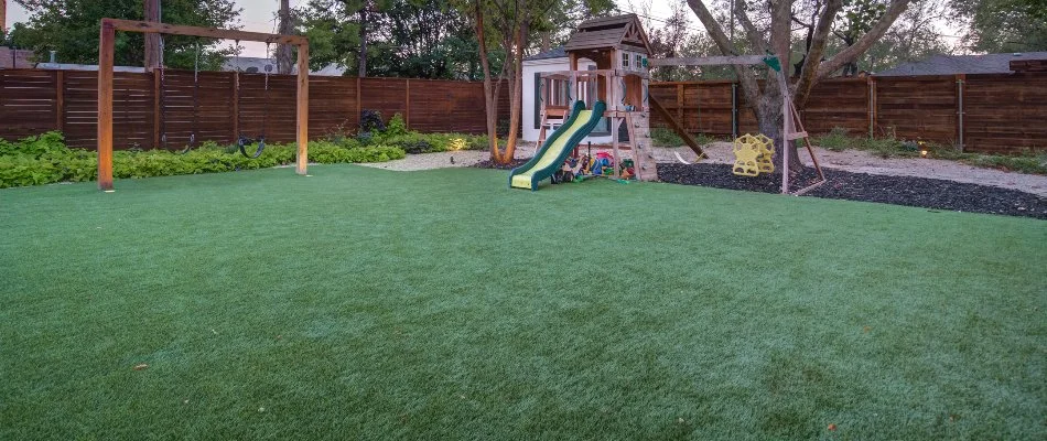 Playground in residential backyard in Lubbock, TX, with artificial turf.