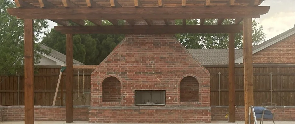 Large, brick outdoor fireplace in Lubbock, TX, with a pergola.