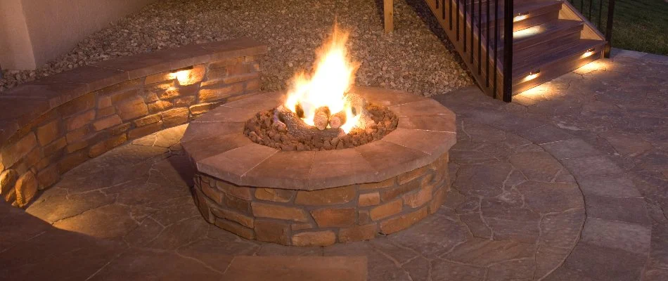 Round fire pit on a patio in Lubbock, TX, with a seating wall.