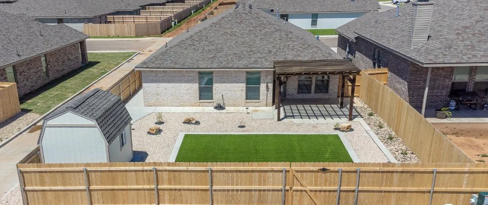 Backyard of a house in Petersburg, TX, with a pergola, artificial turf, shed, and fence.