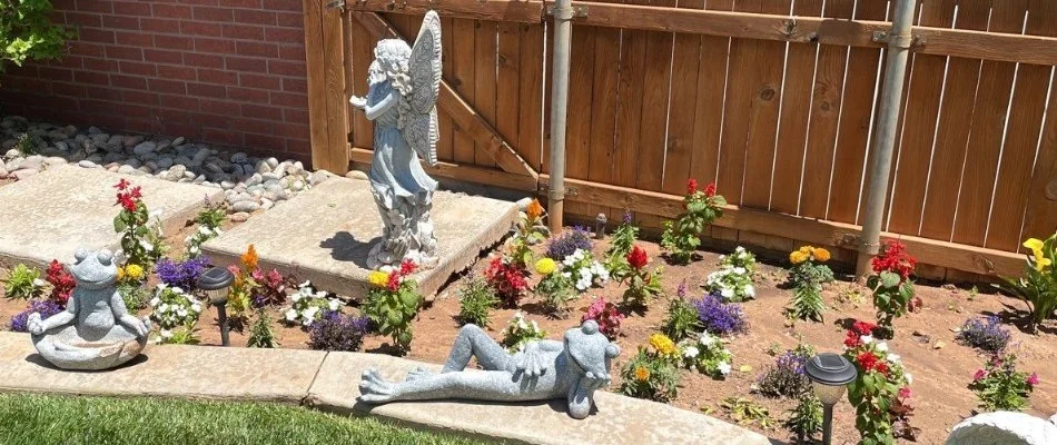 Landscape bed in Lubbock, TX, with flowers and statues.