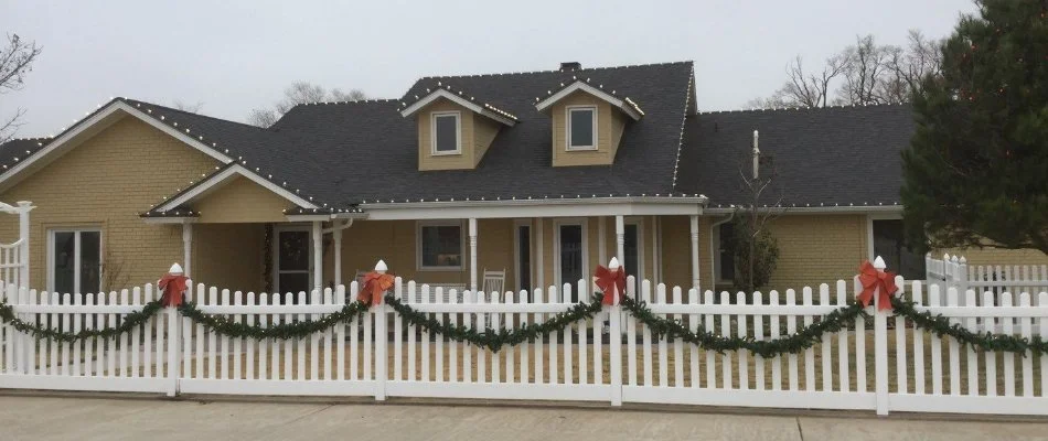 Holiday lighting on a home with decorations on fence in Lubbock, TX.