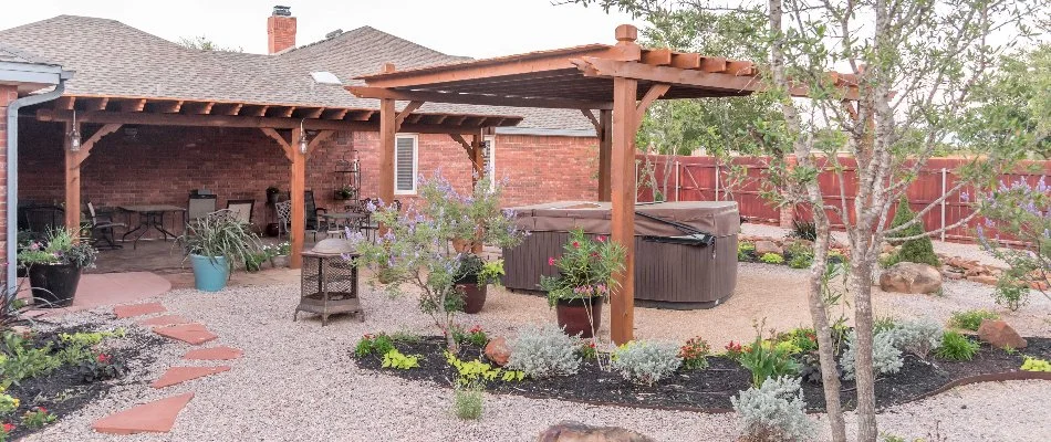 Outdoor space in Lubbock, TX, with a pergola, landscape beds, and plants.