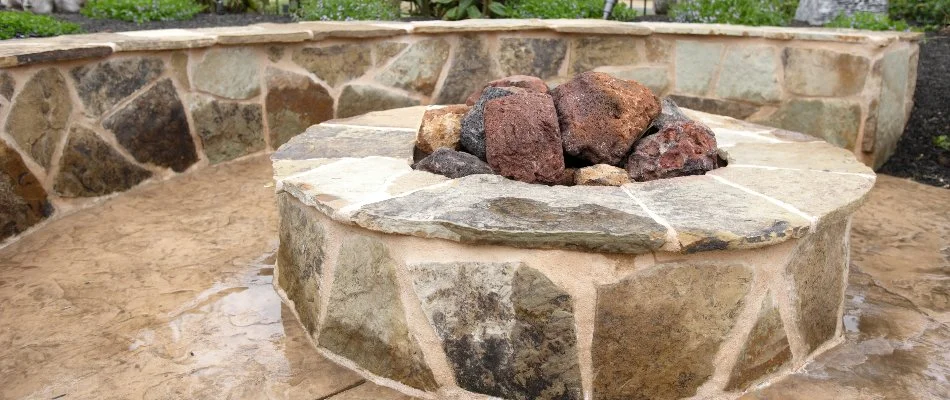 A stone fire pit in Lubbock, TX, with a seating wall.